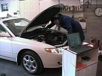 Henry inspects fuel injection system, with laptop connected to OBD system